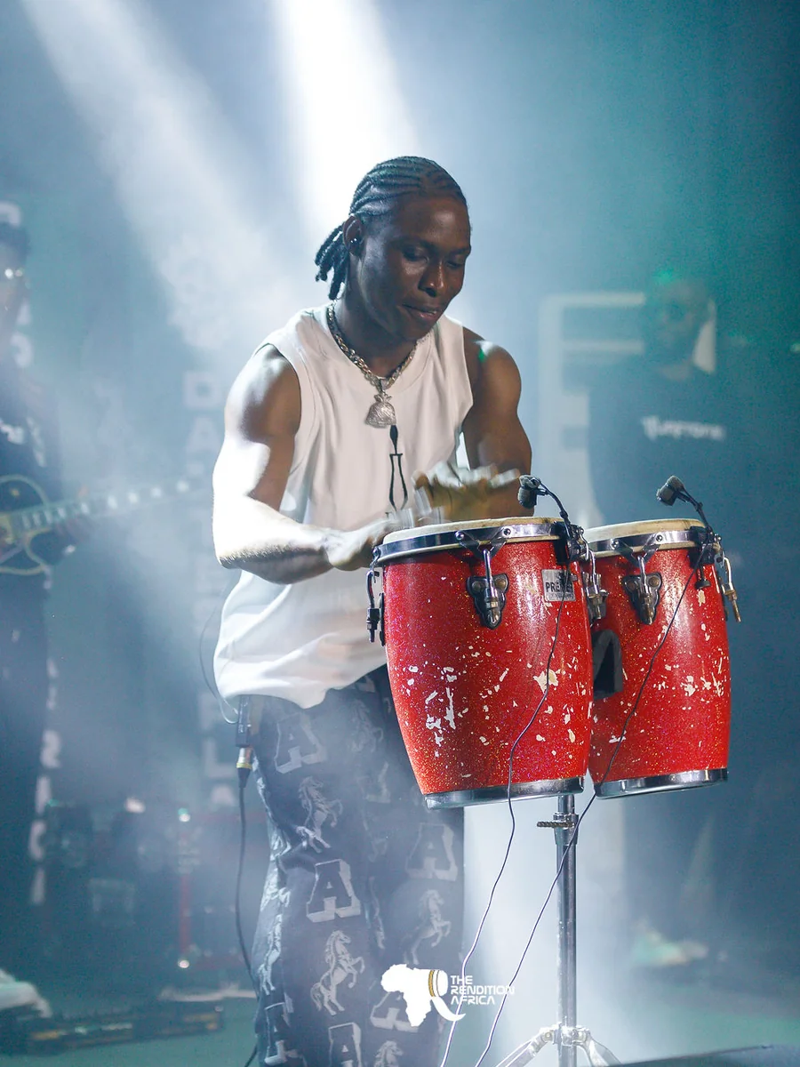 Drumzz playing red conga drums under blue stage lights