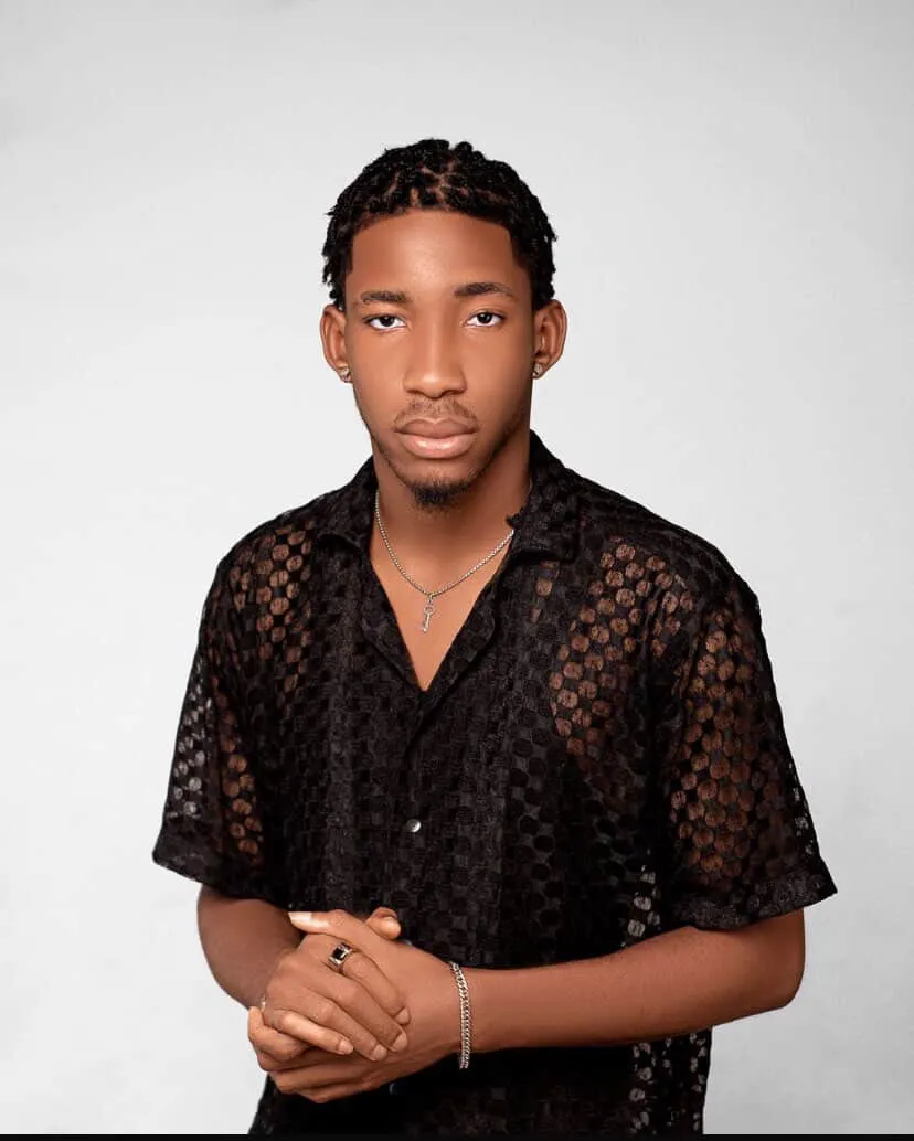 Nite Monster standing in a black patterned shirt against a light gray background