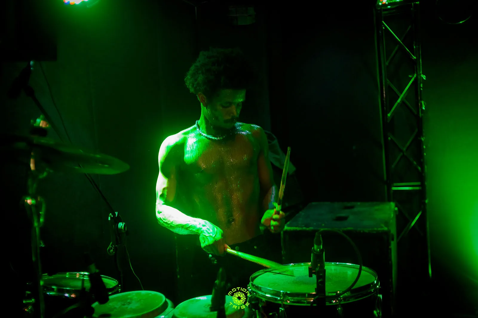 Percussionist plays drums under intense green lighting