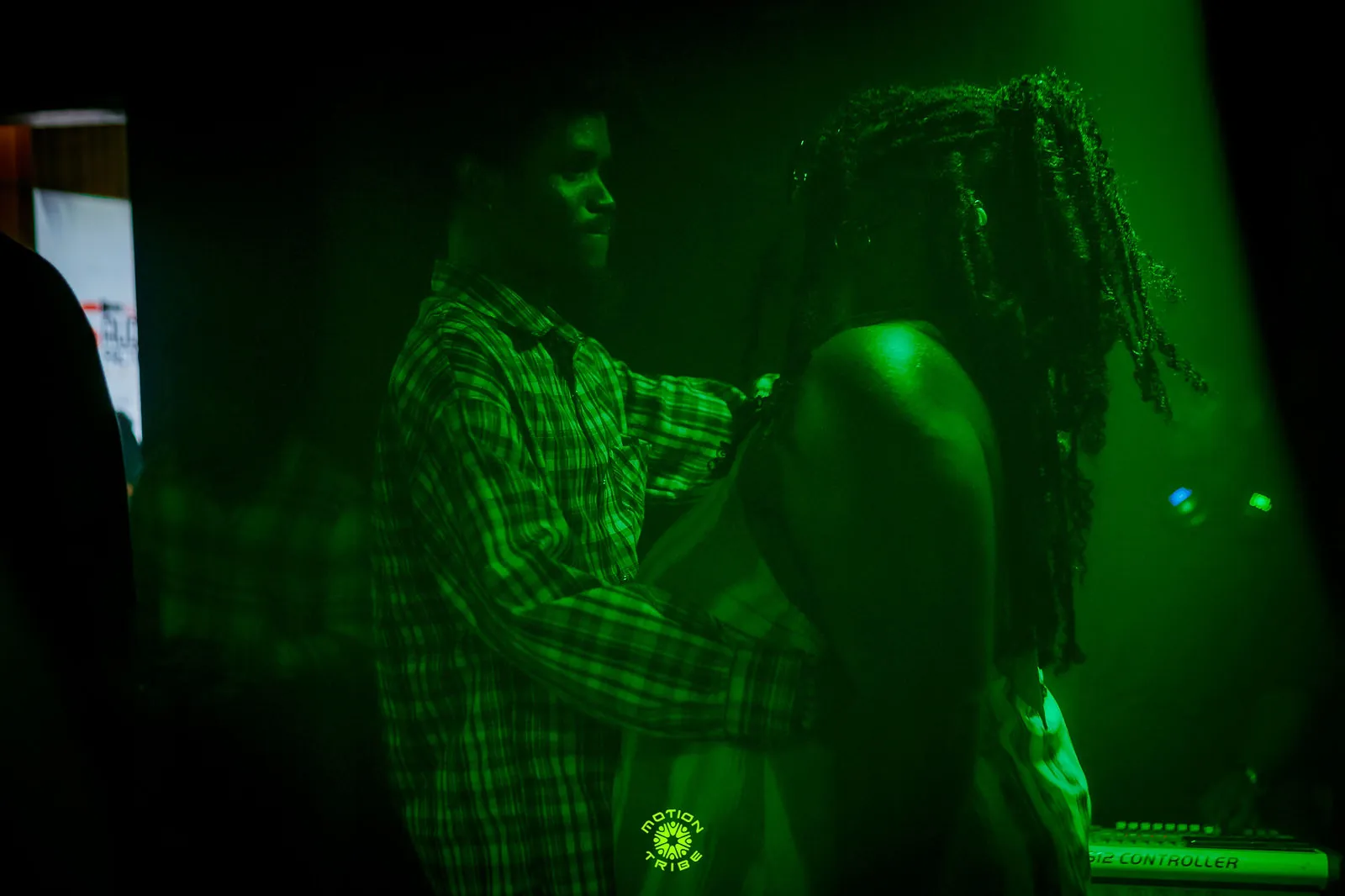 Two ravers face each other closely in the green-lit crowd